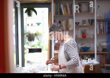 Senior woman in kitchen, organiser pots claire sur la surface de travail Banque D'Images