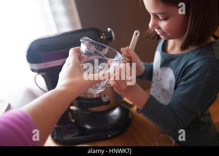 Jeune fille à l'aide de mixeur, mère fille verre gradué, remise Banque D'Images