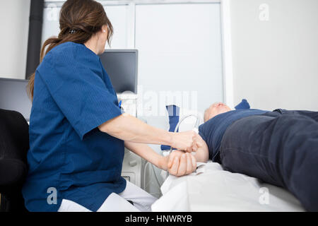 Médecin à l'aide de la sonde à ultrasons sur la main de mâle à l'hôpital Banque D'Images