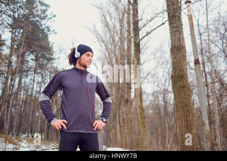 Guy Sports dans les écouteurs et hat au parc Banque D'Images