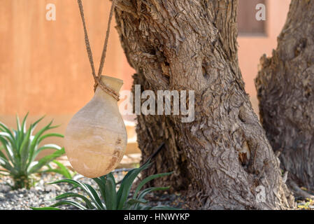 Pot à eau en argile attaché à un arbre avec de la ficelle dans un pays du Moyen-Orient et son environnement désertique Banque D'Images