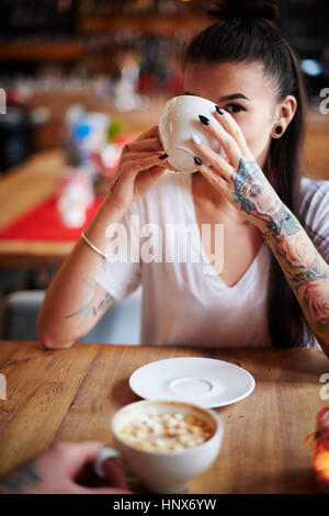 Femme tatouée dans cafe café potable looking at camera
