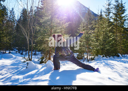 Femme dans les vêtements d'hiver la pratique de l'angle côté yoga pose dans la forêt enneigée, Autriche Banque D'Images