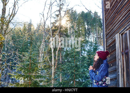 Woman in Knit hat pratiquant le yoga, la méditation par log cabin Banque D'Images