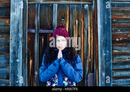 Portrait de femme en Knit hat pratiquant le yoga, la méditation par log cabin door Banque D'Images