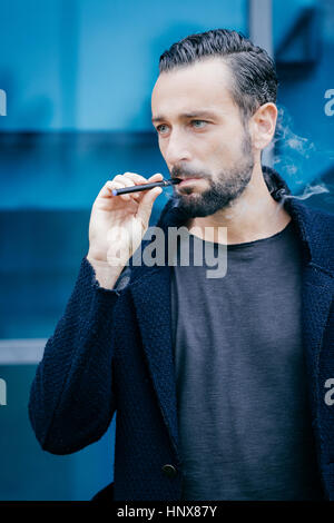 Portrait d'homme qui fume une cigarette électronique Banque D'Images