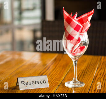 Réservés signe avec un verre de vin sur la table en bois Banque D'Images