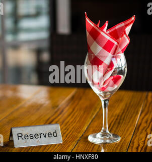 Réservés signe avec un verre de vin sur la table en bois Banque D'Images