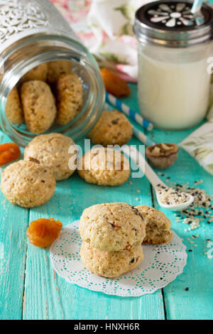 Des aliments sains pour le petit déjeuner. Des biscuits à partir de flocons d'avoine avec des graines de sésame, fruits secs, les noix dans un bocal en verre de lait et on a wooden background Banque D'Images