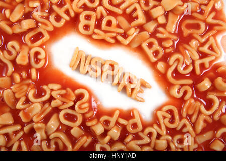 Inspirer écrit en lettres pâtes spaghetti entouré de lettres brouillées. Banque D'Images
