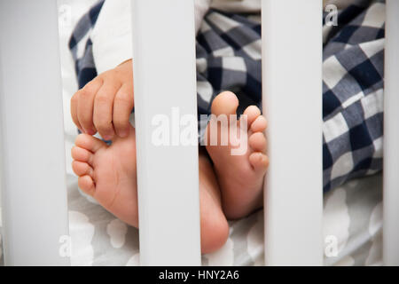 Mon enfant sur un dimanche matin juste réveillé. Fils blottie dans son lit chaud à ses petits pieds alors que dans son pyjama. Serein, heureux et joyeux. Banque D'Images