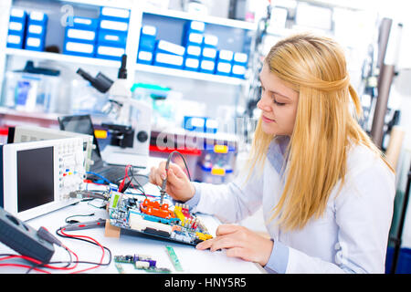 Ingénieur travaillant avec des circuits. Un ingénieur circuits soudures femme assis à une table. Usine de production de Microchip. Processus technologique. L'assemblage Banque D'Images