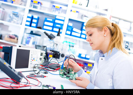 Ingénieur travaillant avec des circuits. Un ingénieur circuits soudures femme assis à une table. Usine de production de Microchip. Processus technologique. L'assemblage Banque D'Images