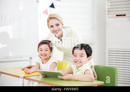 Sourire les enfants de maternelle avec un enseignant étranger Banque D'Images