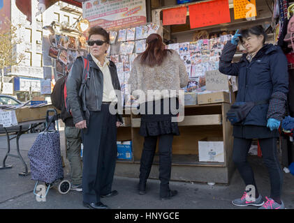 Un homme d'origine asiatique dans une veste en cuir et des lunettes de près d'un stand de DVD dans le quartier chinois, le rinçage, Queens, New York. Banque D'Images