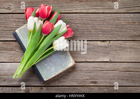 Bouquet de tulipes colorées plus vieux livre sur fond de bois. Rouge et blanc. Avec l'espace pour vos messages d'accueil Banque D'Images