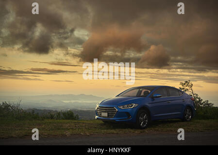 Une voiture bleue garée moderne sur beau coucher de soleil contexte Banque D'Images