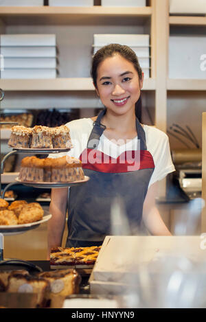 Femme travaillant derrière comptoir de boulangerie, portrait Banque D'Images