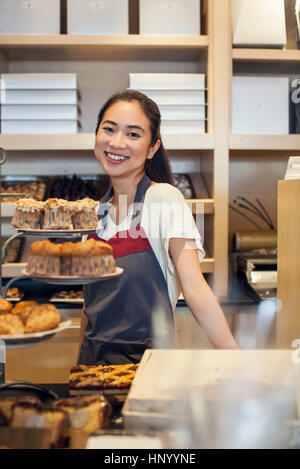 Jeune femme derrière comptoir de boulangerie, portrait Banque D'Images