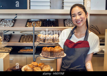 Woman smiling derrière comptoir de boulangerie, portrait Banque D'Images