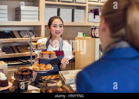 Young woman assisting customer in bakery Banque D'Images