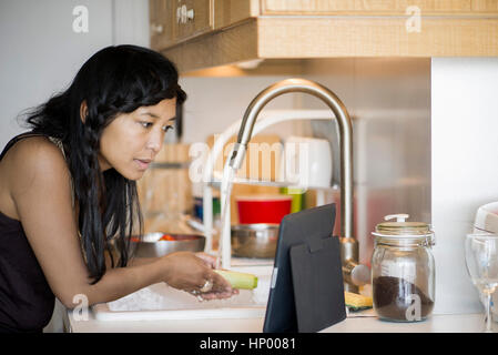 Woman using digital tablet while preparing food at home Banque D'Images