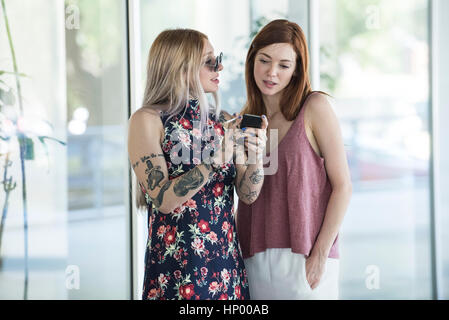 Women looking at smartphone tout en prenant une pause cigarette Banque D'Images