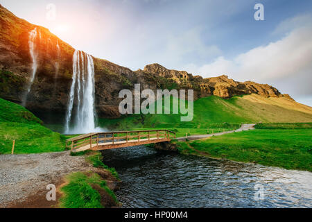 Cascade de Seljalandfoss au coucher du soleil. Pont sur la rivière. Fantas Banque D'Images