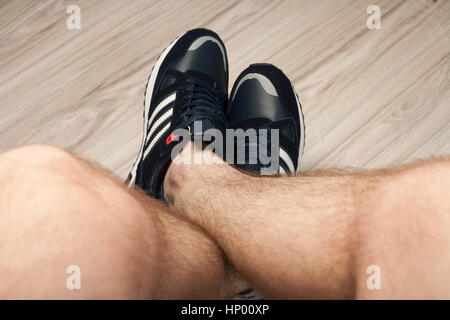 L'homme les jambes poilues dans les chaussures de sport Banque D'Images