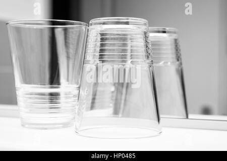 Verres vides se tenir sur la plate-forme blanche près du miroir, noir et blanc photo gros plan Banque D'Images