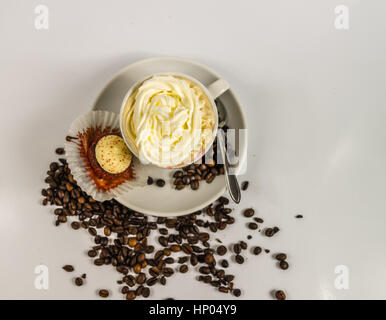 Vue de dessus du café noir dans une tasse blanche sur une soucoupe d'une cuillère de crème fouettée et de crème aux fraises muffin et récupérer les grains de café, la décoration artistique Banque D'Images