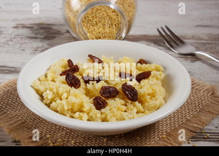 Gruau de millet cuit avec des raisins secs sur plaque blanche, concept d'une saine alimentation, nutrition et petit déjeuner nutritif Banque D'Images