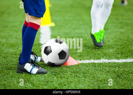 La formation du Football Football des enfants. Jeune athlète avec ballon de football sur terrain. Les enfants au soccer Kicking Ball uniforme. La pratique d'exercices sur les dribbles garçon Sp Banque D'Images