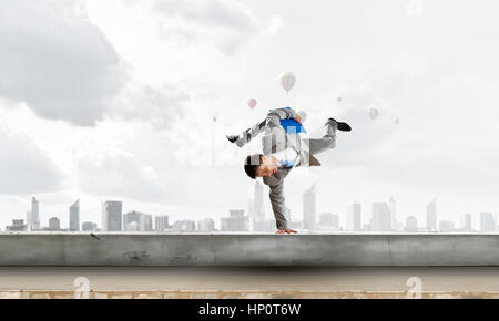 Young cheerful businessman doing handstand sur parapet Banque D'Images