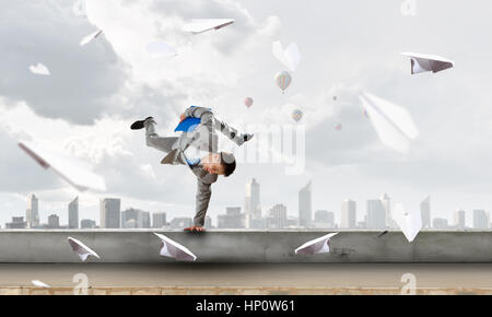 Young cheerful businessman doing handstand sur parapet Banque D'Images