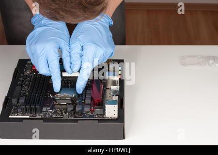 Jeune homme avec des gants de brancher sur la carte mère processeur socket LGA 1151 Banque D'Images