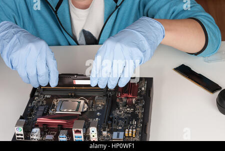 Close up of man mains avec des gants de l'installation de modules de mémoire DDR4 RAM dans l'emplacement sur la carte mère. Banque D'Images