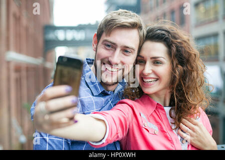 Un couple qui à l'extérieur ensemble selfies Banque D'Images