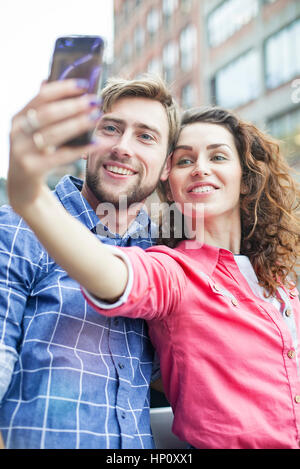 Un couple qui à l'extérieur ensemble selfies Banque D'Images