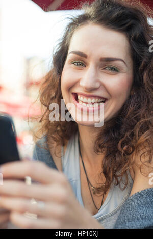 Young woman using smartphone, smiling, portrait Banque D'Images