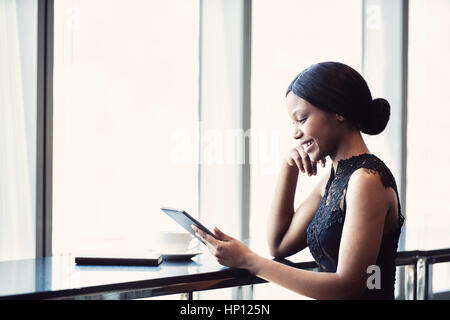 African woman smiling tout en maintenant et en regardant une tablette Banque D'Images