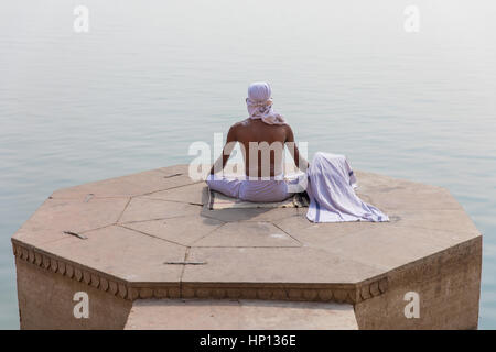 Un homme médite sur le Gange à Varanasi, une des villes les plus saintes de l'Inde. Varanasi est une destination populaire pour les touristes qui fréquentent les écoles de yoga. Banque D'Images