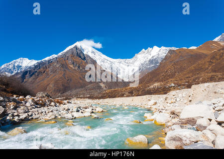 Vue paysage de Langtang Lirung, pointe une partie de snow-capped Himalaya derrière courant rapide de la rivière de l'eau glaciaire en altitude au Népal. Banque D'Images