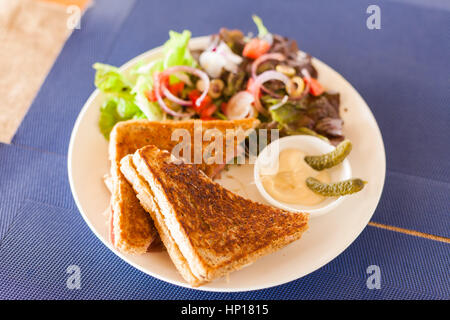 Croque-monsieur au sandwich avec salade et oignons caramélisés dans un café Banque D'Images