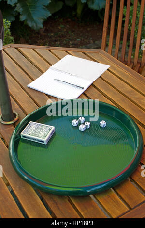 cinq 5 petits dés blancs et jeu de cartes sur plateau vert sur table en bois avec carnet et stylo à côté, prêt pour les joueurs à commencer le jeu Banque D'Images