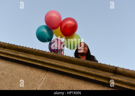 Londres, Royaume-Uni. Feb 17, 2017. Une femme portant des ballons d'anniversaire est éclairé par le soleil derrière le Parlement et Big Ben à Westminster après une journée de beau temps. Crédit : Stephen Chung/Alamy Live News Banque D'Images