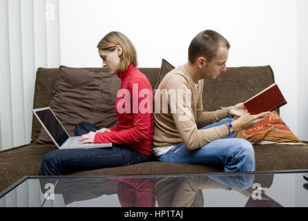 Modèle libération , Frau arbeitet suis Ordinateur, Mann liest ein Buch - woman using laptop, Man reading a book Banque D'Images