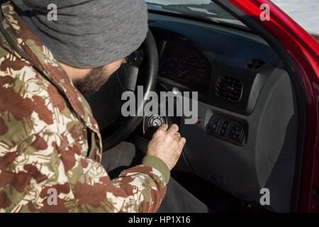 Voiture de départ en hiver. L'homme de la cap met les clés sur le contact de la voiture. Le démarrage du véhicule dans des conditions hivernales. Banque D'Images