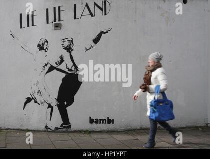 Une femme passe devant un morceau de street art par l'artiste Bambi, intitulé mentir mentir Land - représentant le premier ministre Theresa mai et le président américain, Donald Trump, dansant dans une pose parodiant le film La La Land - à Islington, Londres. Banque D'Images