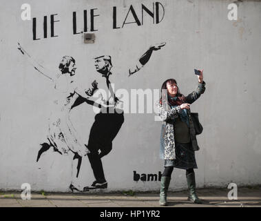 Une femme prend un en face de selfies un morceau de street art par l'artiste Bambi, intitulé mentir mentir Land - représentant le premier ministre Theresa mai et le président américain, Donald Trump, dansant dans une pose parodiant le film La La Land - à Islington, Londres. Banque D'Images